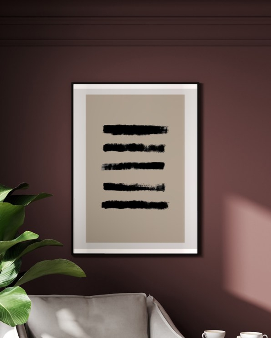 Painted Bands poster in a slim black frame on a deep burgundy wall above a cream armchair