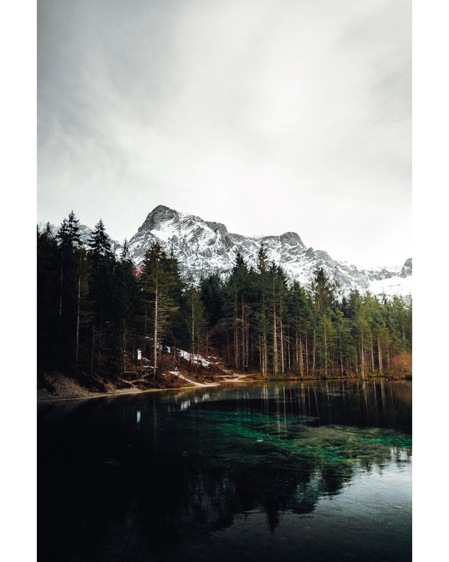 Mountain lake with forest and snowy peaks reflected