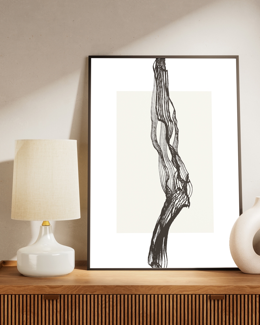 A poster of black tree branch on a beige background placed on a brown table