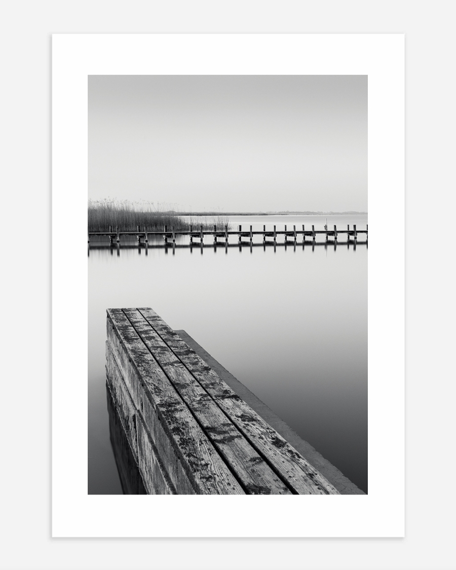 A poster of a Wooden pier reflected in calm black and white water