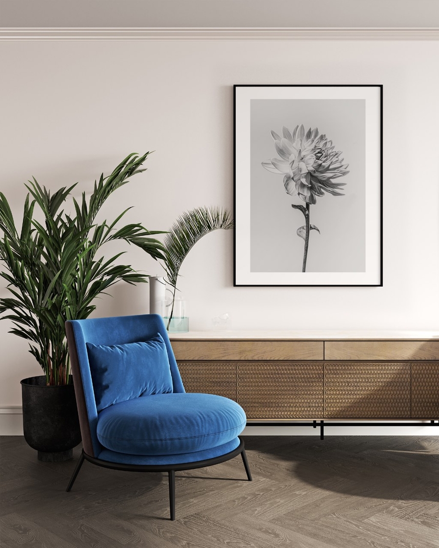Silver Dahlia poster in a slim black frame above a wooden sideboard beside a blue armchair