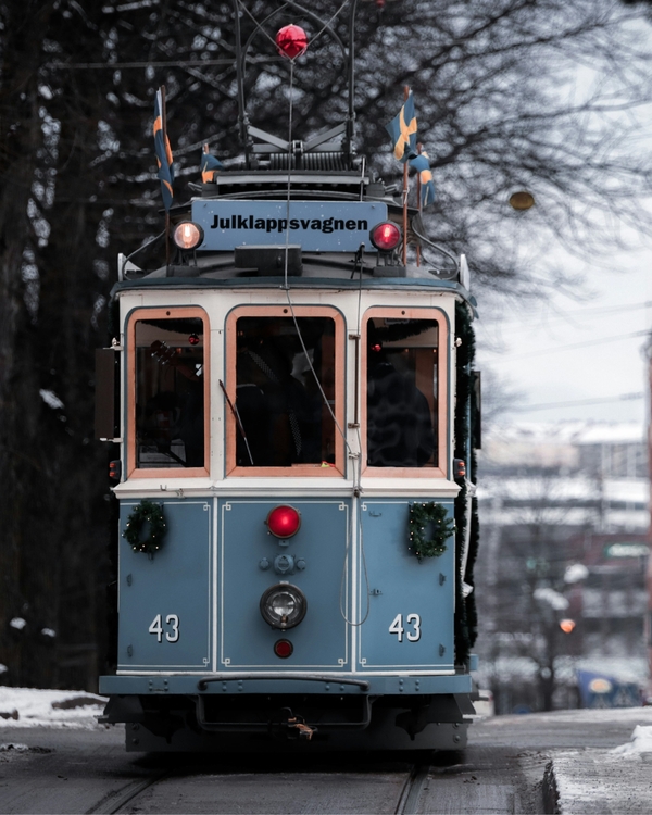 Blue vintage tram decorated for Christmas on snowy street