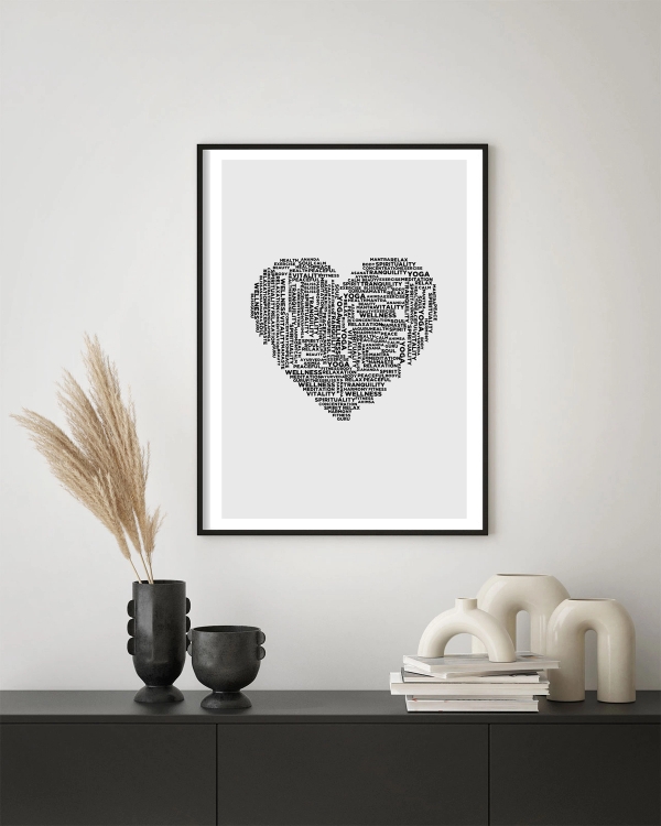 A poster of a heart-shaped figure made with words such as yoga and love hanged on a white wall over a table