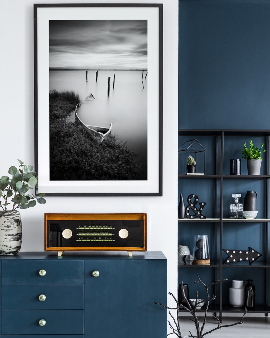 Forgotten Rowboat poster in a slim black frame above a deep blue sideboard with a vintage radio