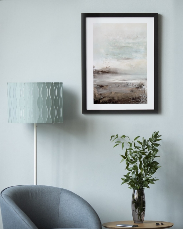 Weathered Plain poster in a black frame on a pale blue wall above a chair and plant