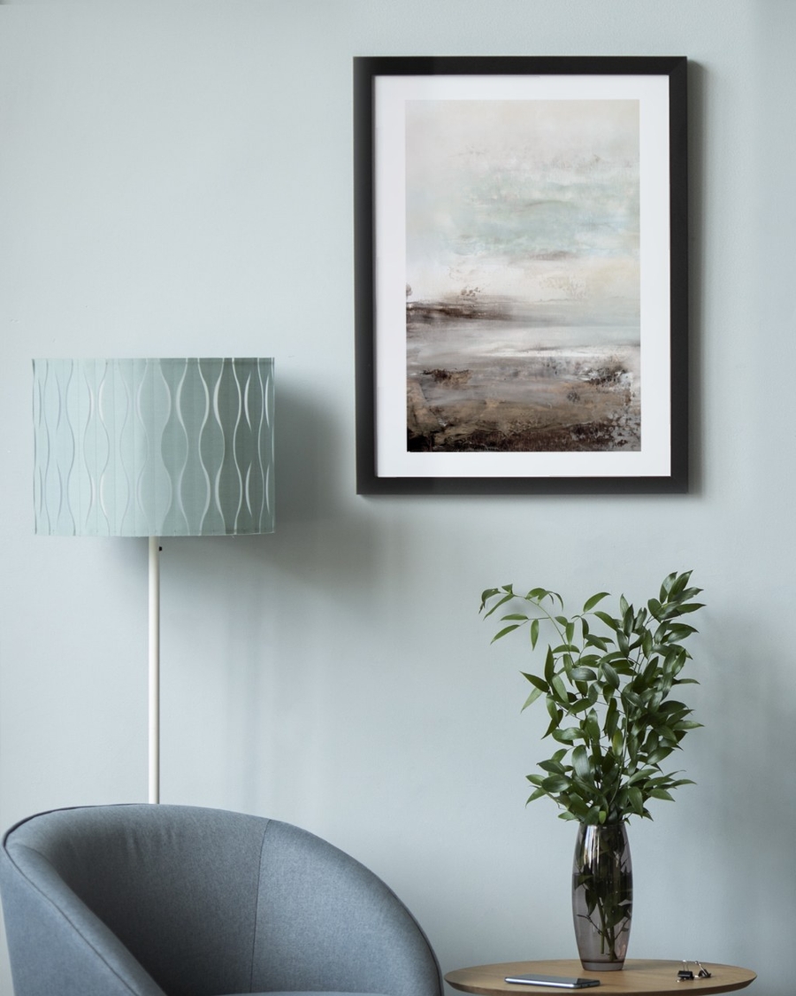 Weathered Plain poster in a black frame on a pale blue wall above a chair and plant