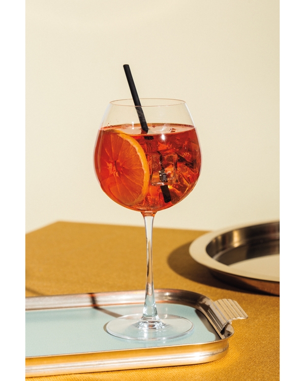 Orange cocktail in wine glass on tray