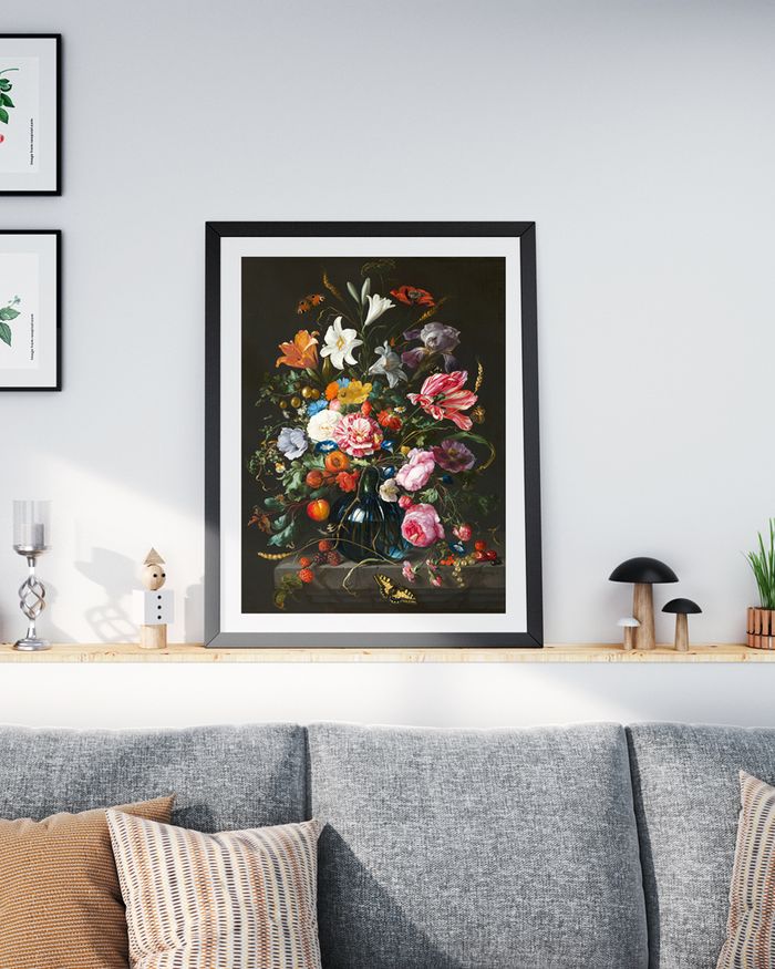 A framed poster of vintage painting of floral in a glass vase on a white wall