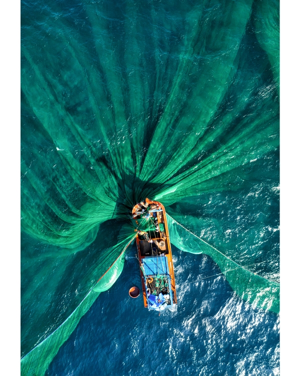 Aerial view of fishing boat with green nets spread.