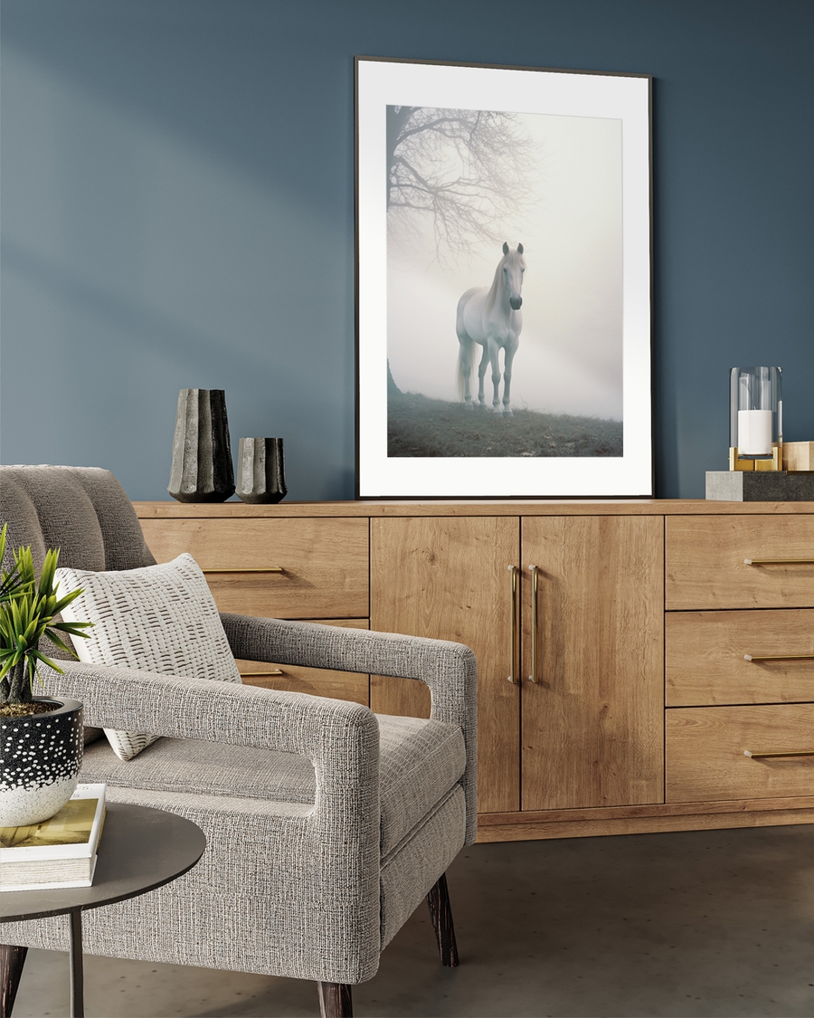A poster of a White horse standing in soft fog near bare tree