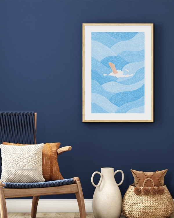 Blue Plunge poster in a light oak frame on a deep navy wall above a wooden lounge chair