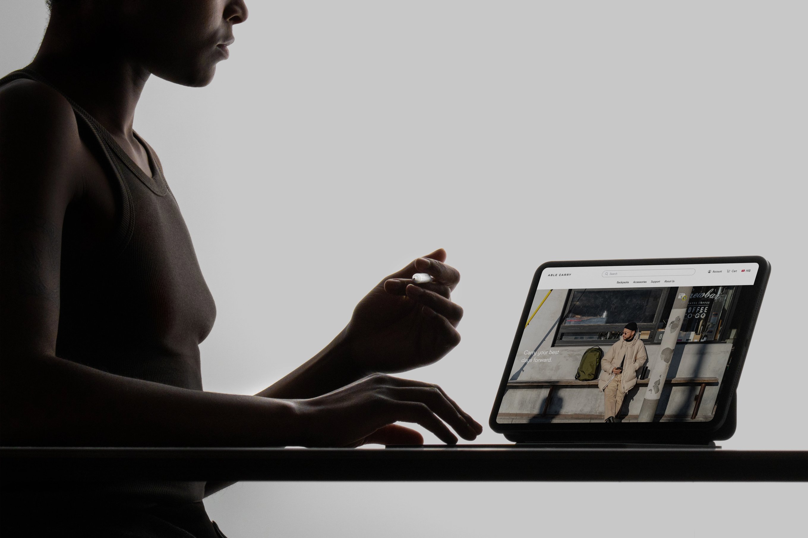 A woman sitting in front of a desk, interacting with the Able Carry website on an iPad Pro.