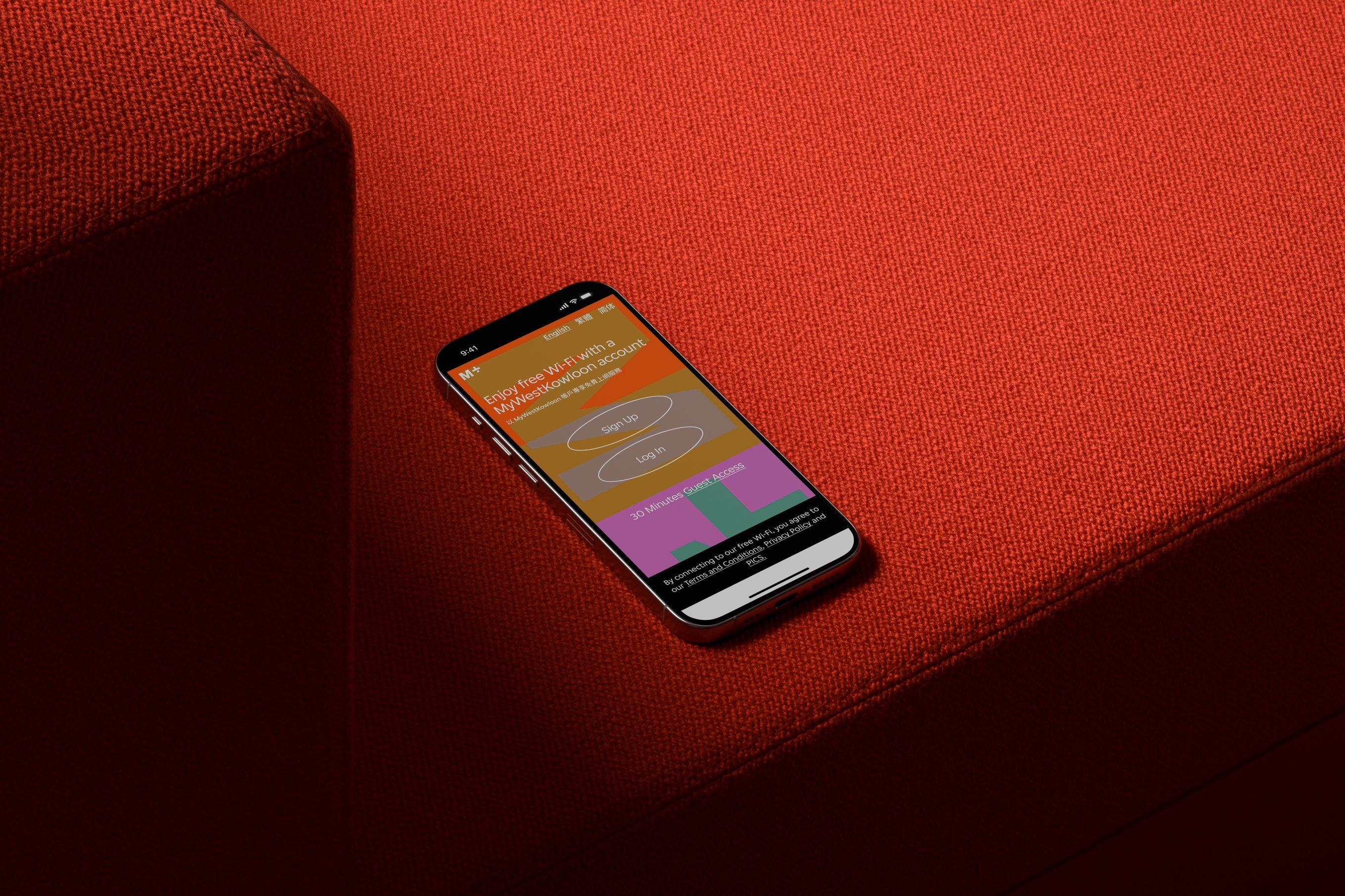 A mock-up of the M+ Wi-Fi interface displayed on an iPhone placed on a sofa.