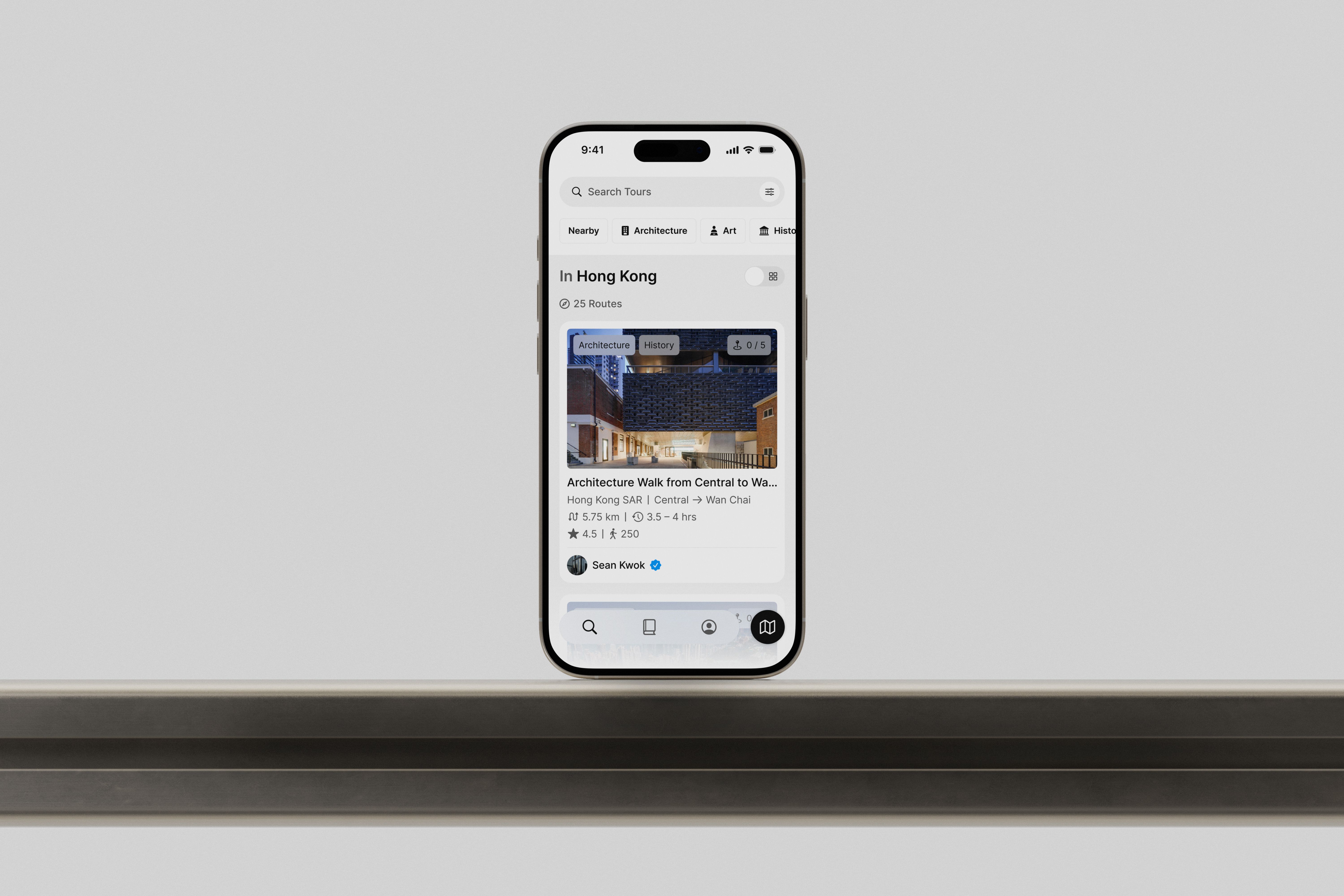 An iPhone on a metal desk featuring the Many Roads app design.