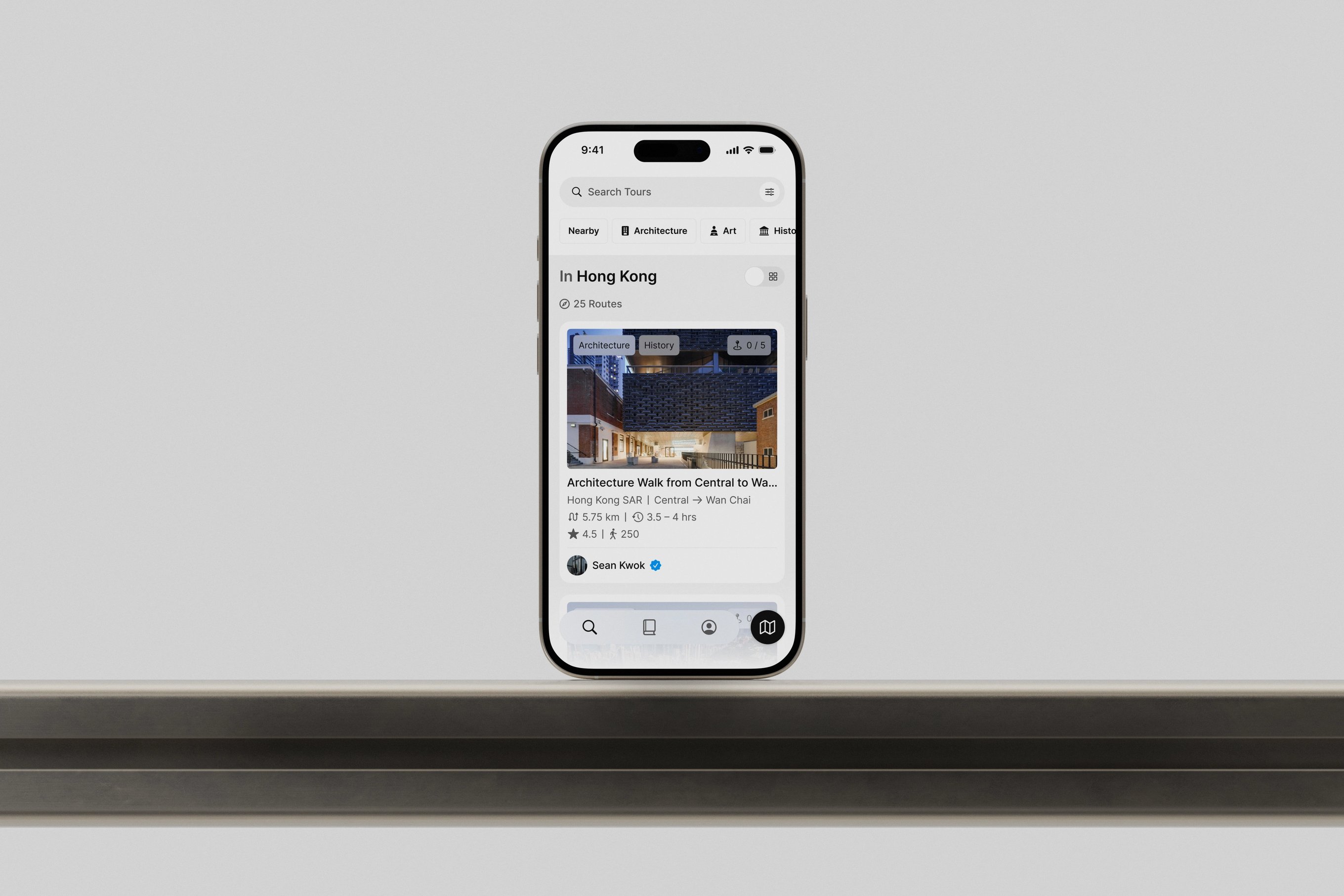 An iPhone on a metal desk featuring the Many Roads app design.