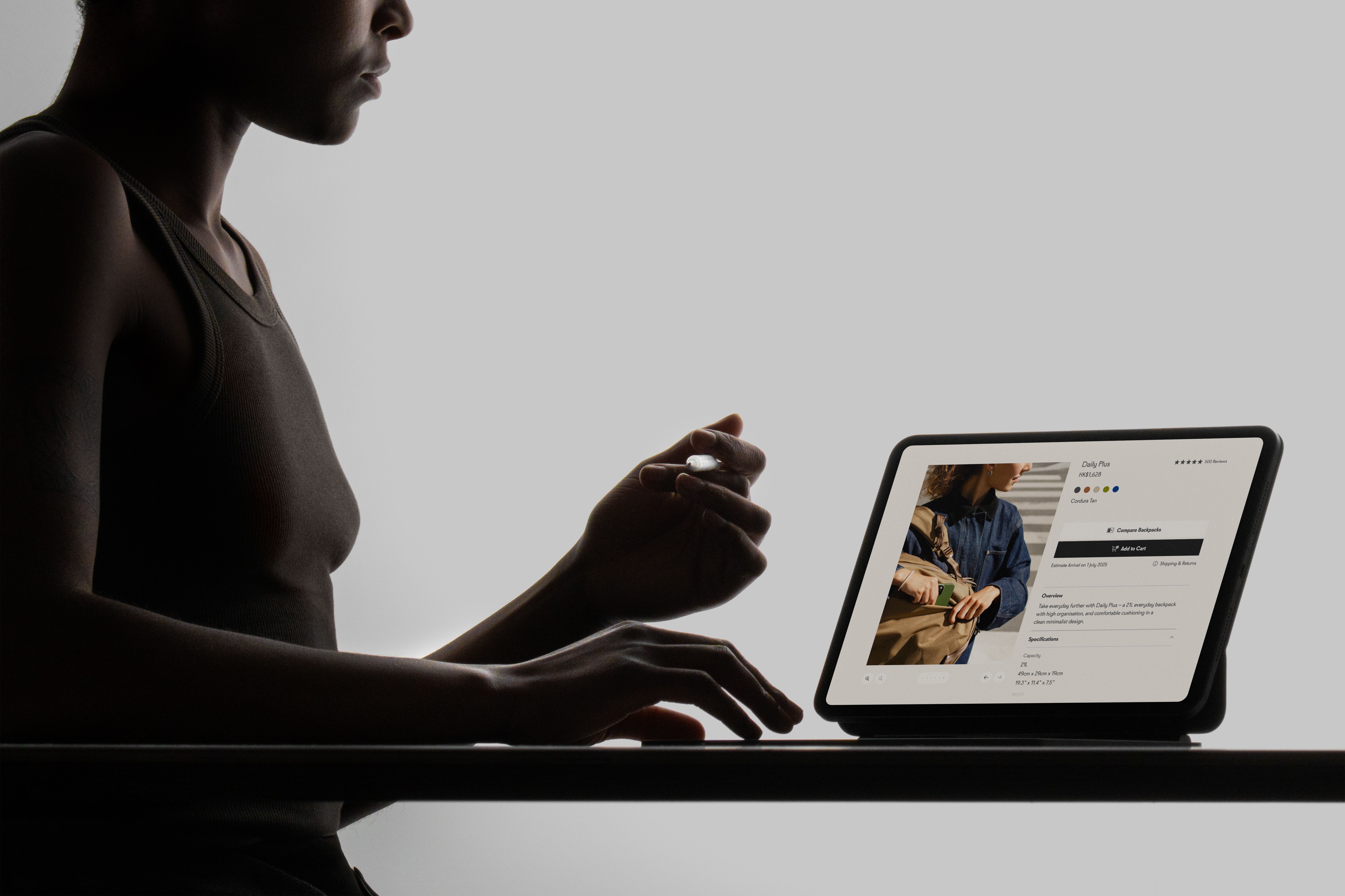 A woman sitting in front of a desk, interacting with the Able Carry website on an iPad Pro.