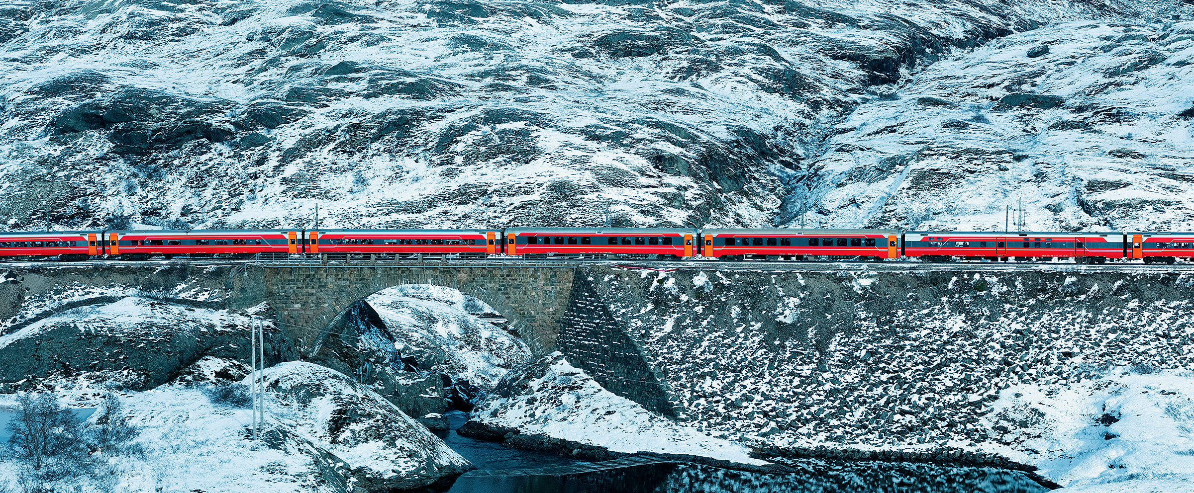 A train passing a lake in a snowy mountain landscape
