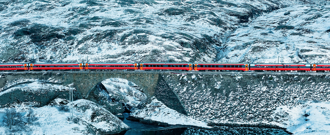 A train passing a lake in a snowy mountain landscape