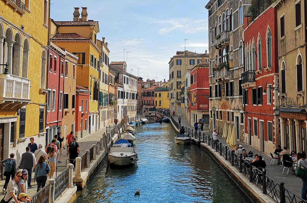 En kanal i Venezia med hus på begge sider. En kanalbåt ligger i vannet.