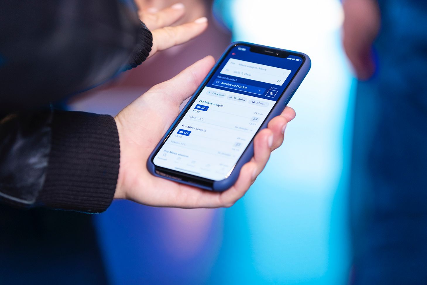 Bilde av en hånd som holder opp en mobiltelefon innlogget på Entur-appen.