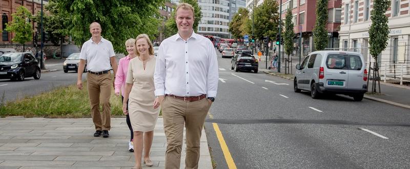 Bilde av fire personer som spaserer langs en bilvei.