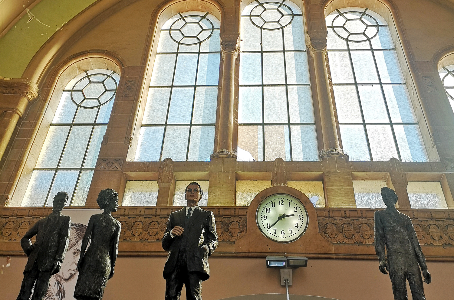 Togstasjonen i Metz. Statuer og en stasjonsklokke foran store ærverdige vinduer