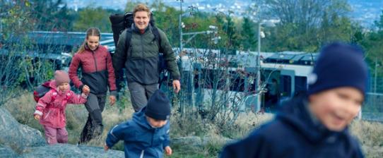En familie, mann, kvinne tre barn i alderen 3-5 har gått av kollektivtransport, med turutstyr. Foto