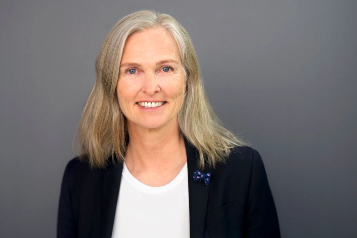 Portrett av Christel Borge som smiler og ser rett inn i kamera. Hun har på seg en svart blazer og hvit topp.