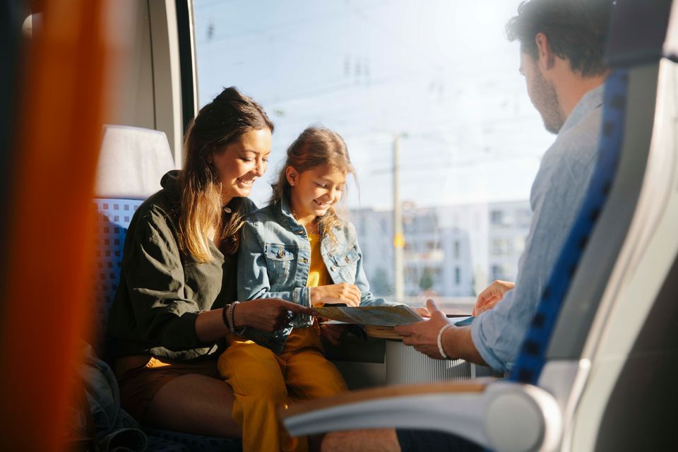 Bilde av en familie, en mor, en far og en datter på rundt 10 år som sitter i en togvogn.