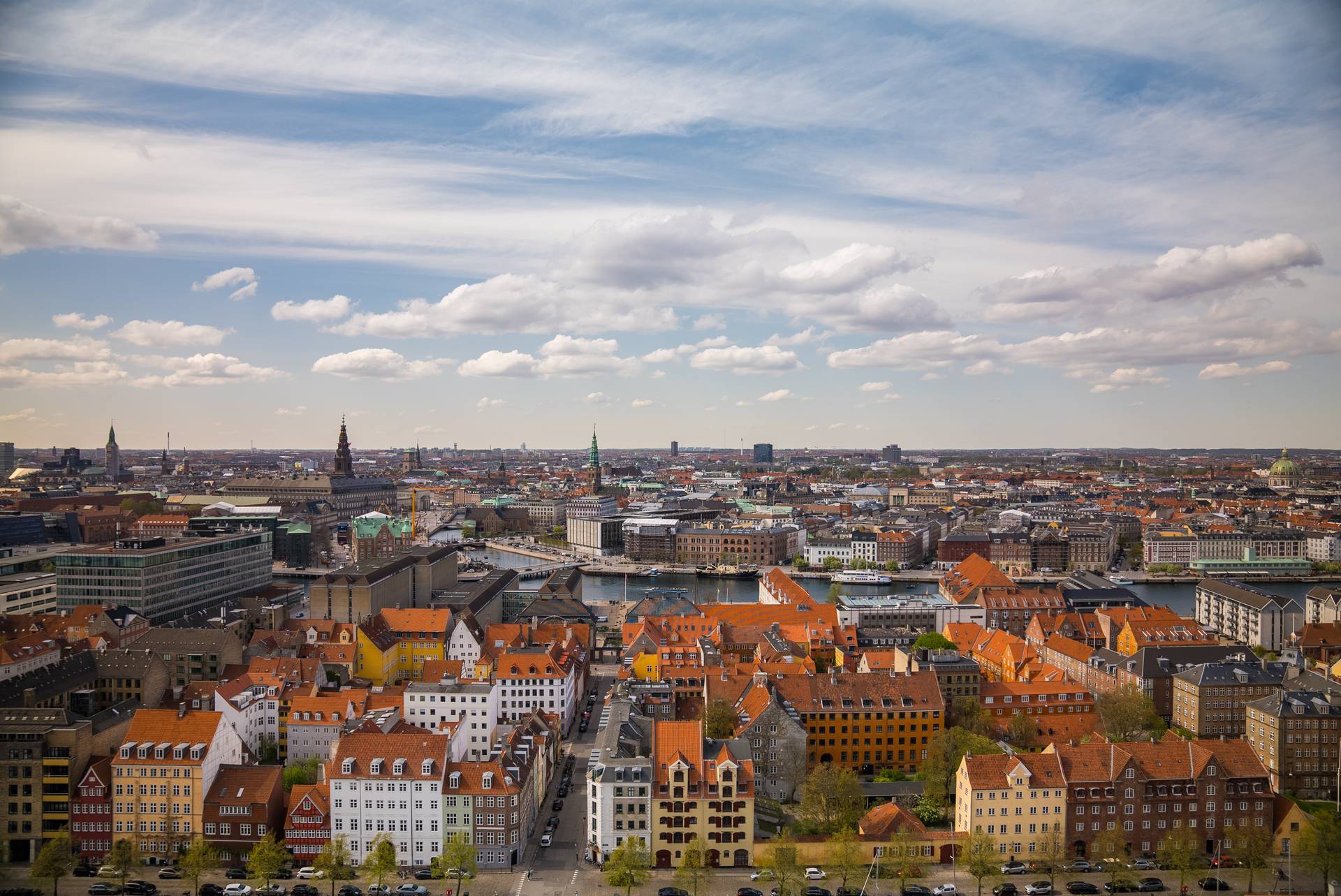 Utsikt over København med dei karakteristiske raude tegltaka, kanalane og tårna i byen under ein delvis skya himmel.