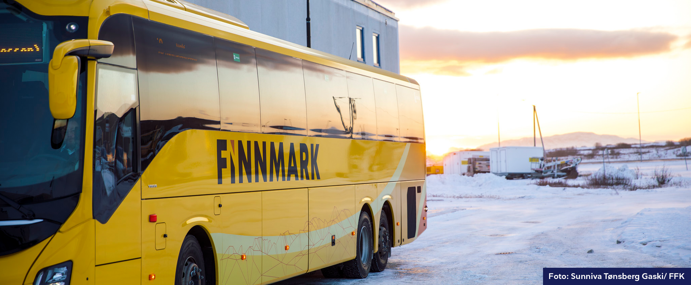 Bilde av et snødekt landskap og en rødmende himmel. Høyre side av bildet domineres av en gul buss med påskriften "Finnmark".