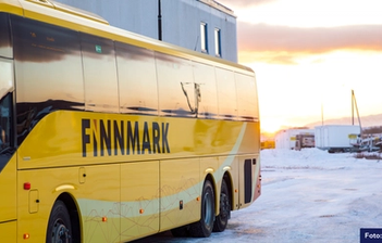 Bilde av et snødekt landskap og en rødmende himmel. Høyre side av bildet domineres av en gul buss med påskriften "Finnmark". 