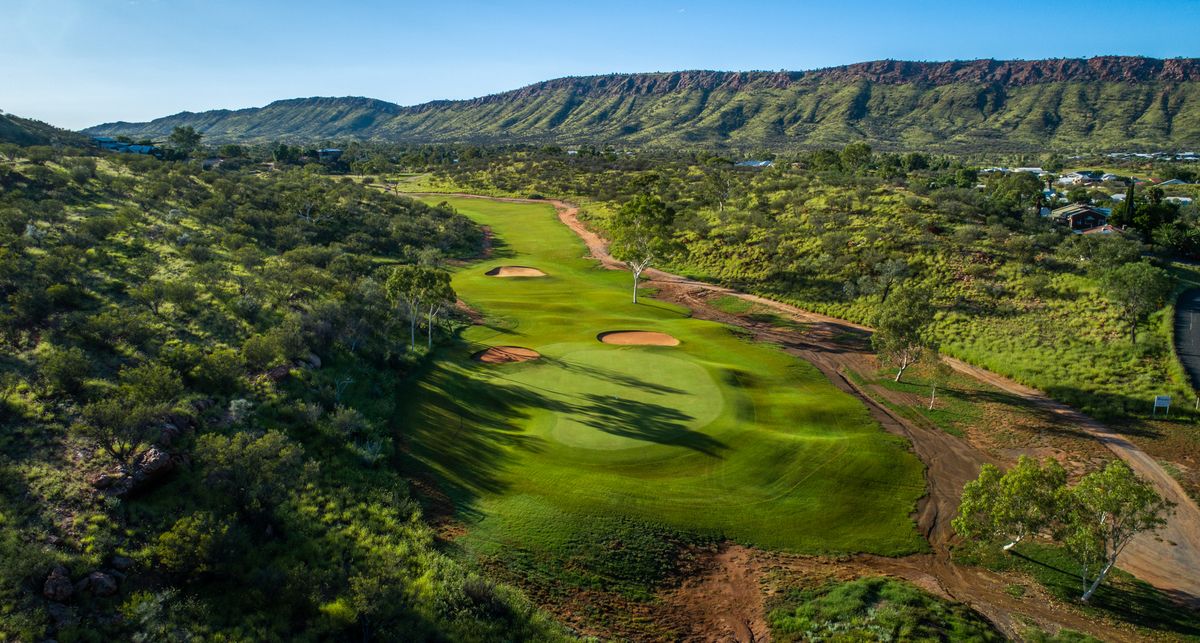Aerial view of a green with bunkers at Alice Springs Golf Club, set among red desert ranges and eucalypts.