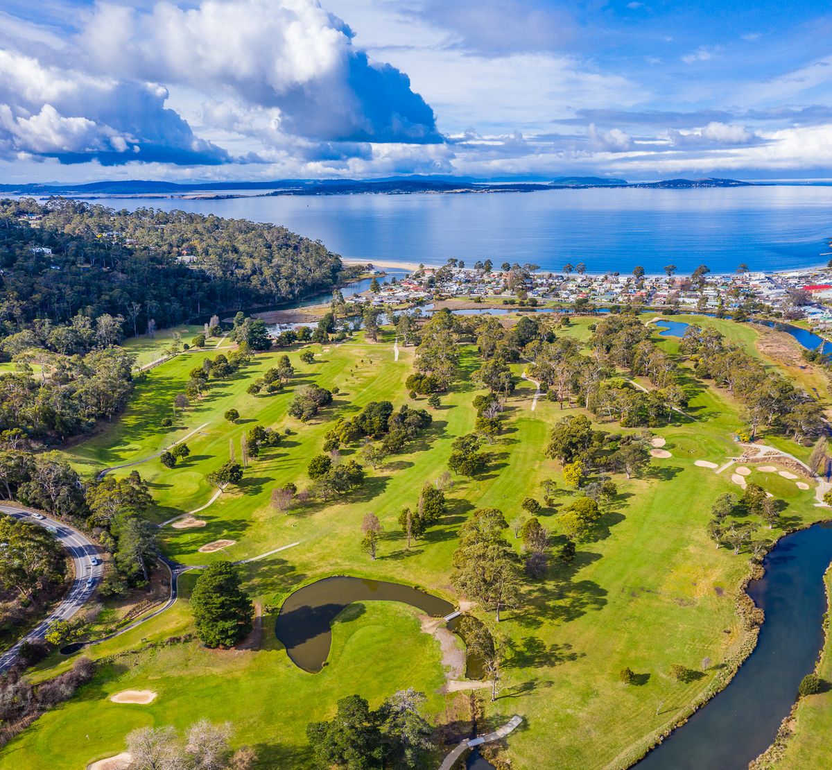 Aerial view of Kingston Beach Golf Club's tree-lined fairways beside the river and coastline
