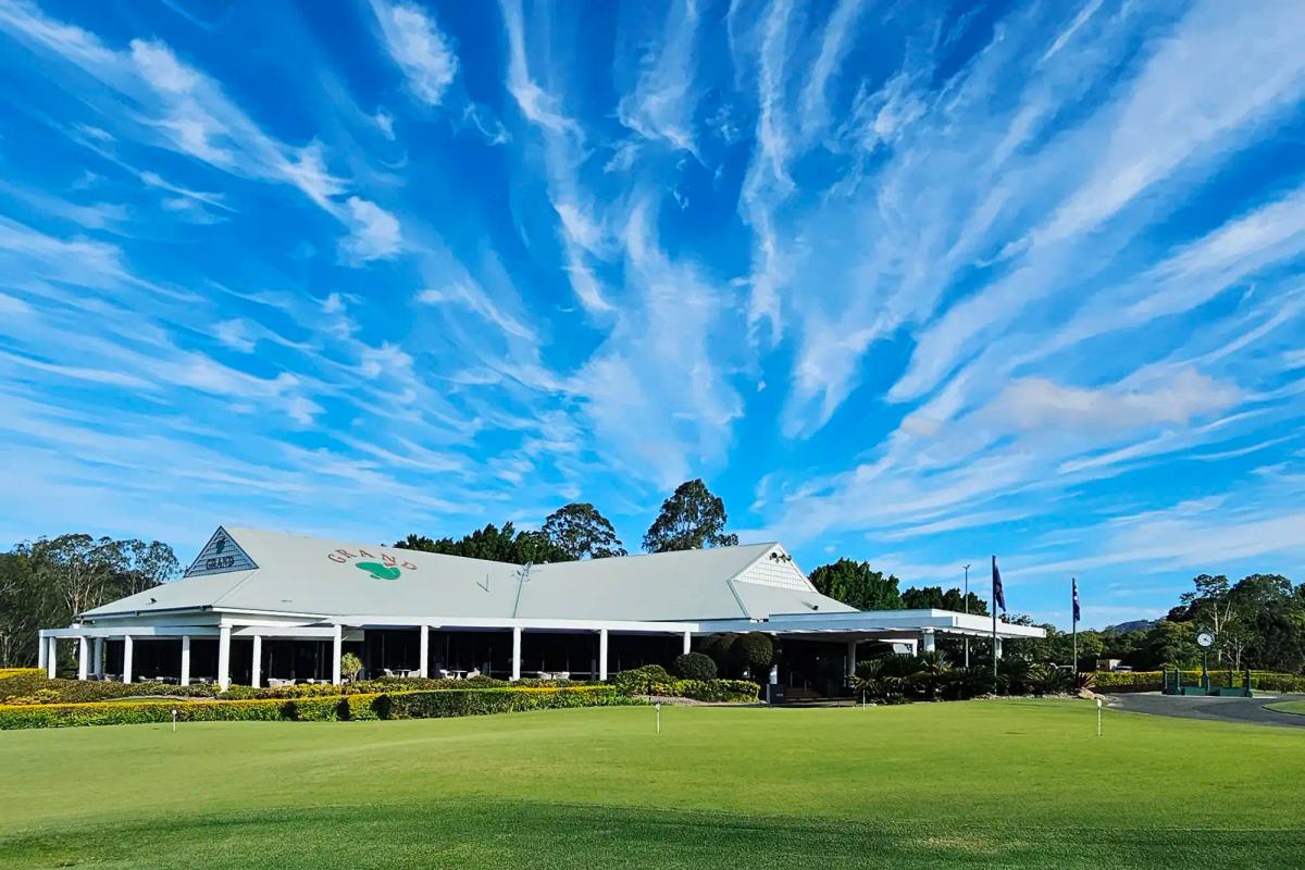 The clubhouse and practice green at The Grand Golf Club, Queensland, under a wide blue sky