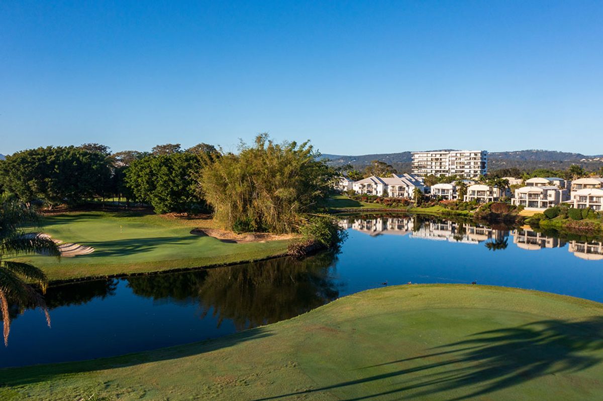 Green and lake at Palm Meadows Golf Course with Gold Coast apartments in the background