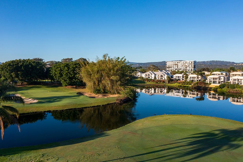 Green and lake at Palm Meadows Golf Course with Gold Coast apartments in the background