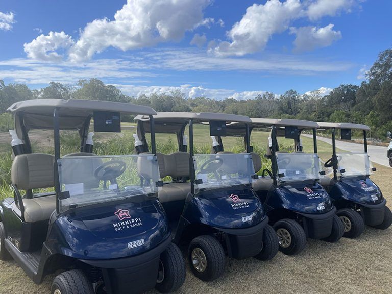 A row of golf carts branded with the Minnippi Golf & Range logo on the course