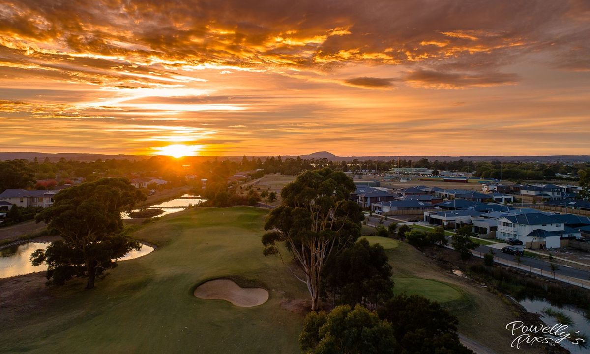 Aerial sunset view of a green and bunker at Ballarat Golf Club, with ponds and surrounding suburbs in the background.