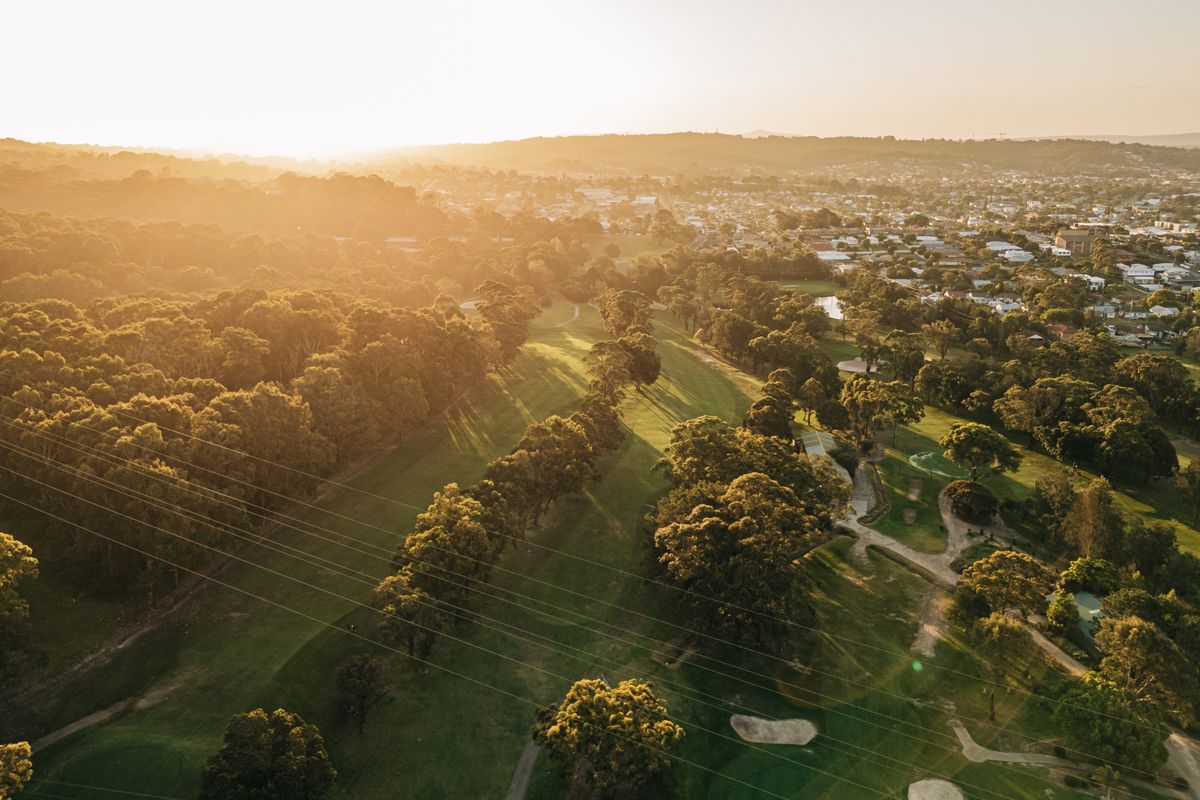 Aerial sunset view of tree-lined fairways and bunkers at Merewether Golf Club