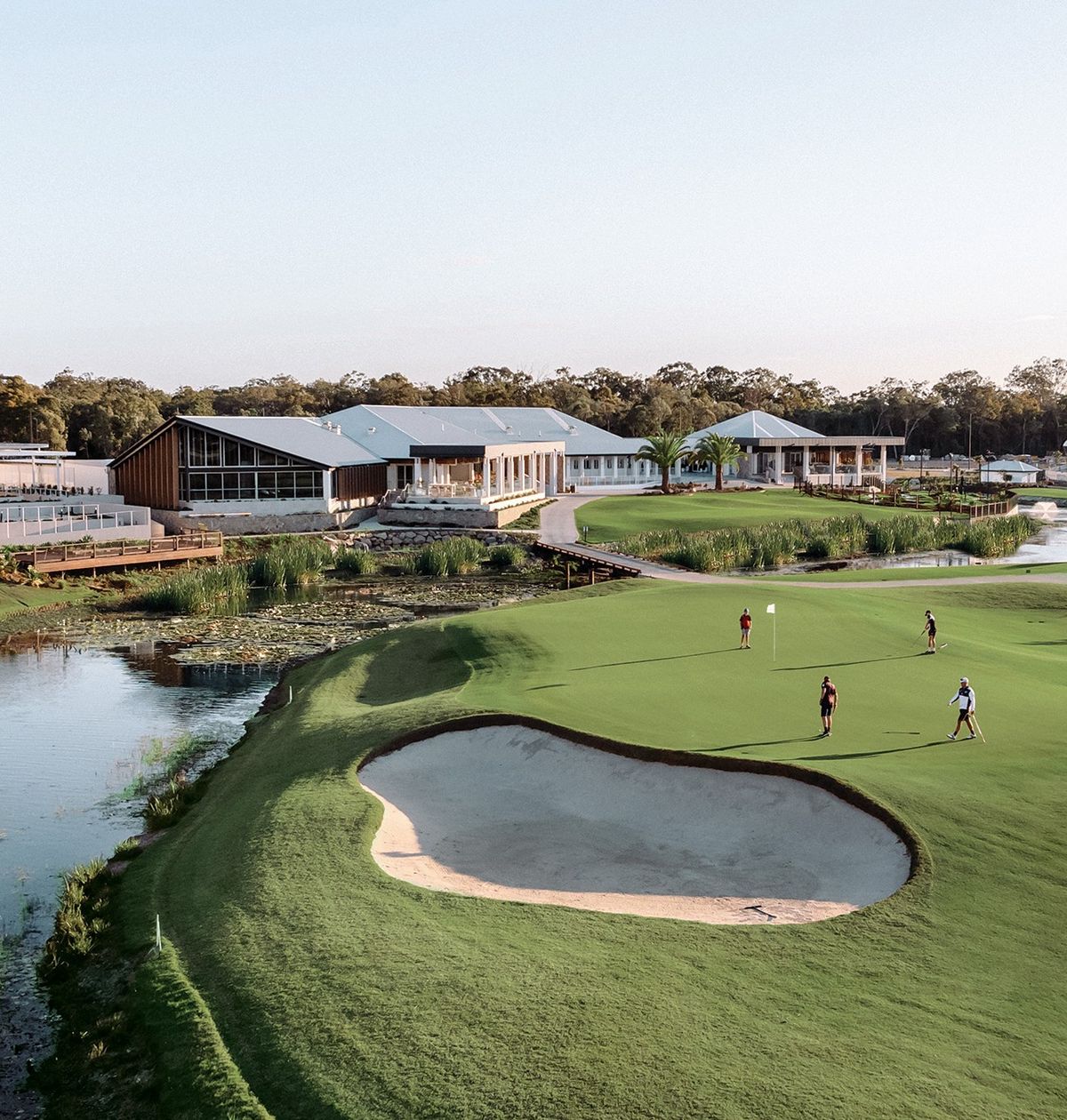 Clubhouse, bunker and green beside the lake at Pelican Waters Golf Club