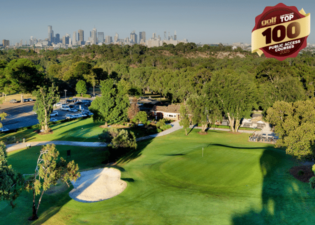 Aerial view of a green and bunker at Yarra Bend Golf course with the Melbourne city skyline visible in the distance.