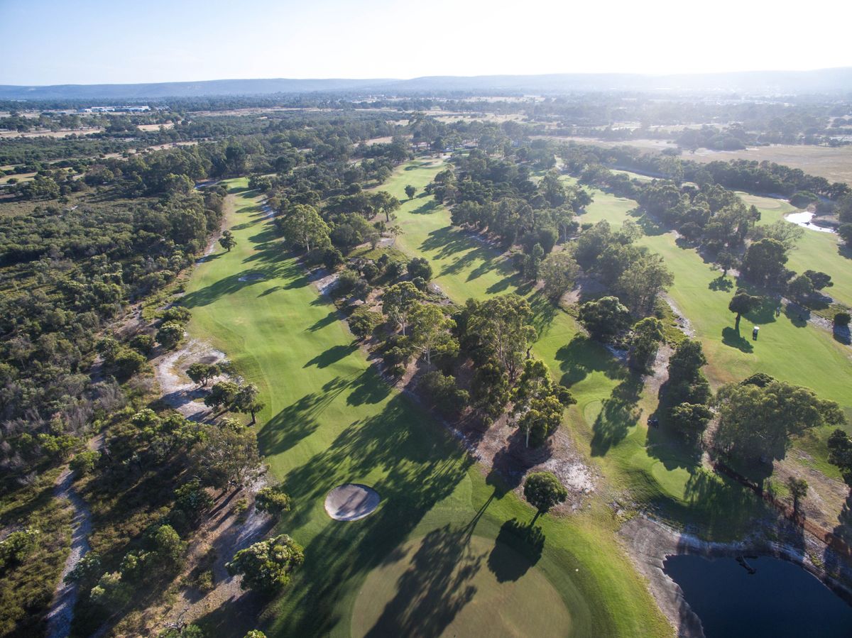 Aerial view of a fairway with bunkers and a pond at The Springs Club in Armadale, surrounded by bushland.