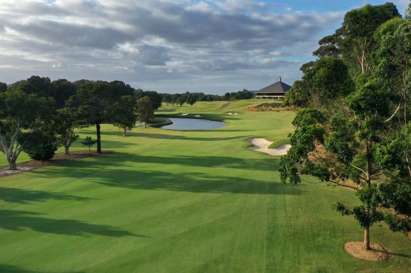 A fairway leading to a green with a pond and the clubhouse at The Australian Golf Club, Sydney