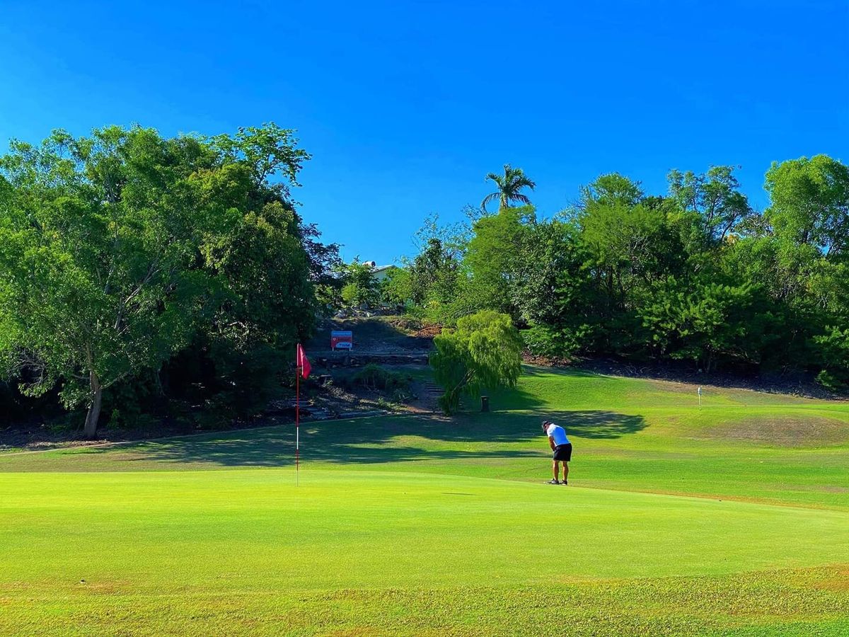 A golfer putting on the green with the flag flying at Gardens Park Golf Links in Darwin