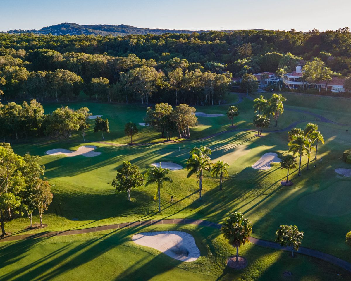 Aerial view of Noosa Springs Golf Course fairways, bunkers and clubhouse among palm trees