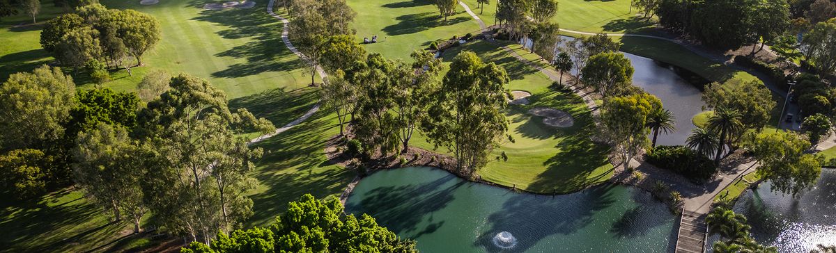 Aerial view of a green surrounded by bunkers and a lake at Emerald Lakes Golf Club