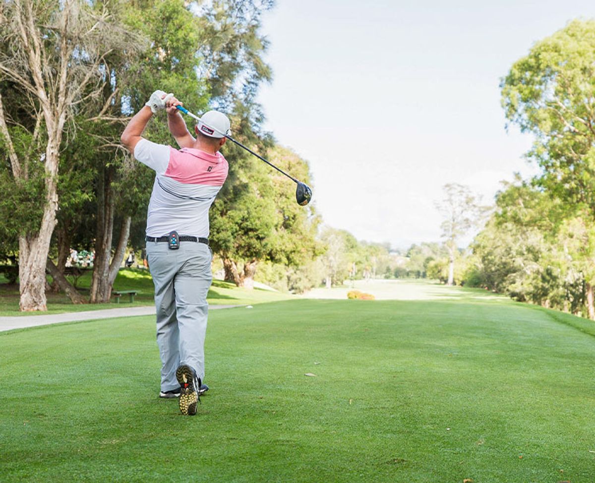 A golfer teeing off down a tree-lined fairway at Moruya Golf Club