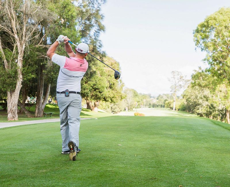 A golfer teeing off down a tree-lined fairway at Moruya Golf Club
