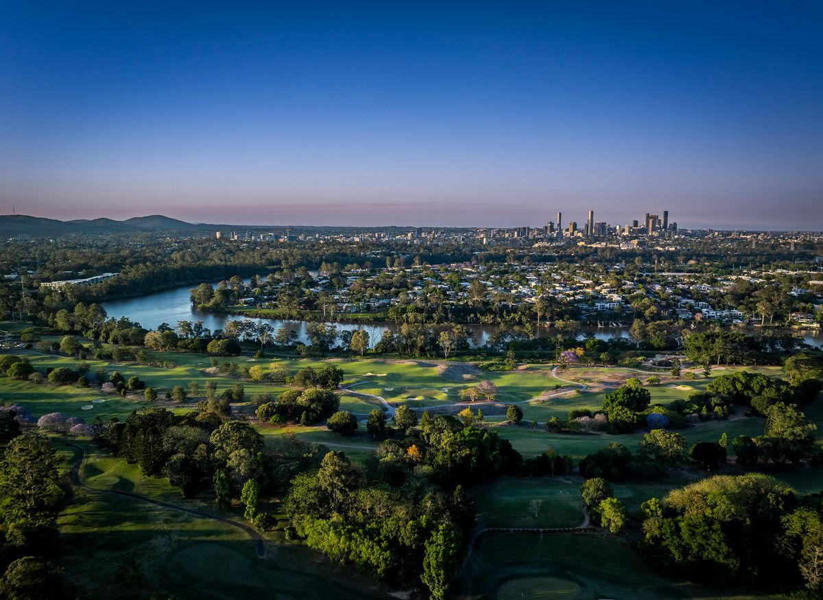 Aerial view of Indooroopilly Golf Club's fairways beside the Brisbane River, with the city skyline in the distance